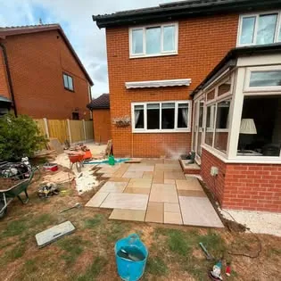 Finished Indian sandstone patio laid by JK Paving & Surfacing against a red brick house in South Yorkshire