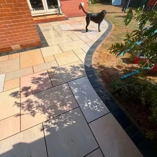 Completed Indian sandstone patio and lawn area with curved charcoal edging